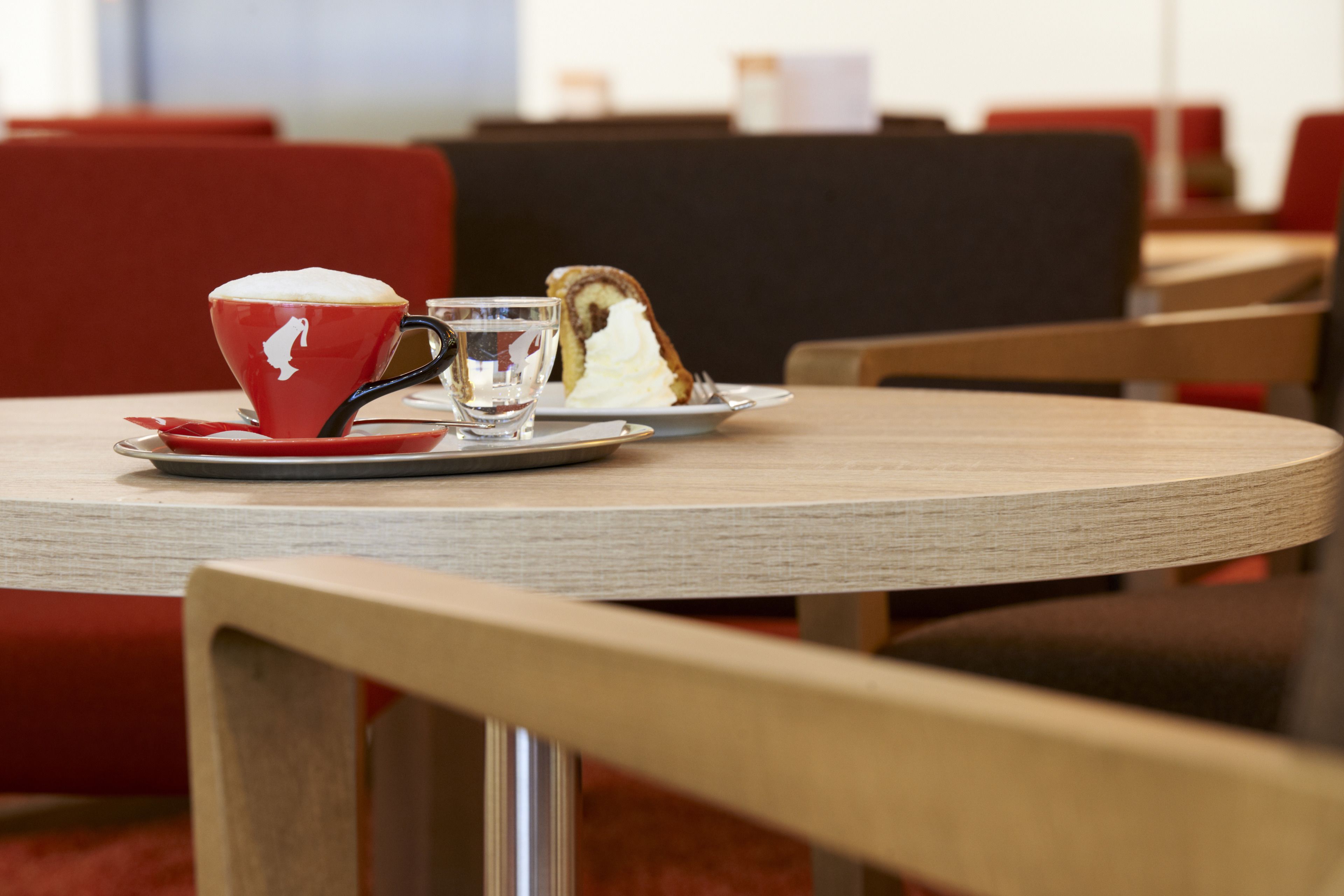 A table with a red cup, a glass, and a slice of cake.