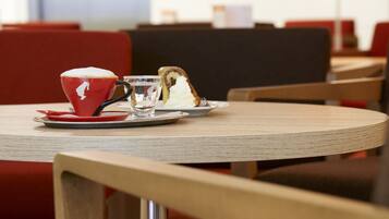 A table with a red cup, a glass, and a slice of cake.