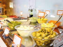 Buffet com diversos alimentos, incluindo azeitonas, fatias de limão e uma tigela com comida branca.
