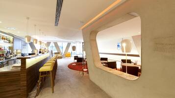 Een modern interieur met een bar, zitplaatsen en een opvallend architectonisch detail.