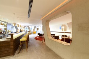 Um interior moderno com área de bar, assentos e um detalhe arquitetônico único.