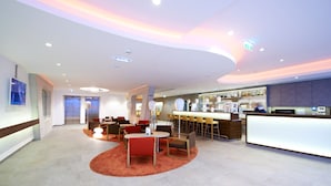 Un moderno vestíbulo de hotel con una recepción, zona de estar y un bar.