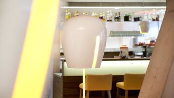 A modern interior with a bar area, bar stools, and a unique spherical light fixture.