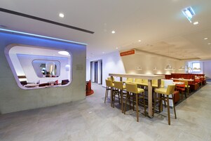 Un restaurante moderno con una barra central, varias mesas para comer y sillas.