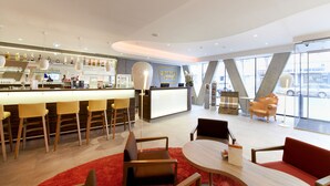 Un moderno vestíbulo de hotel con zona de bar, arreglos de asientos y grandes ventanales que ofrecen vistas al exterior.