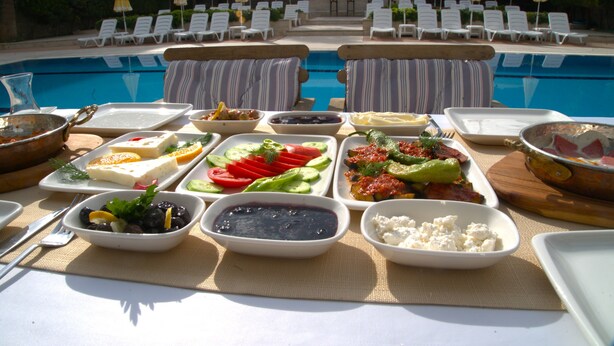 A poolside buffet with various dishes and a pool in the background. - Happy Apart (Kusadasi)