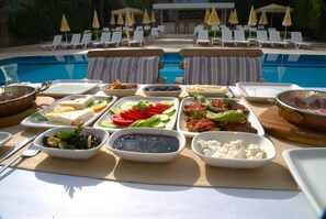 A poolside buffet with various dishes and a pool in the background. - Happy Apart (Kusadasi)