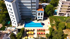 A high-rise building with a rooftop pool, multiple balconies, and surrounding greenery. - Happy Apart (Kusadasi)
