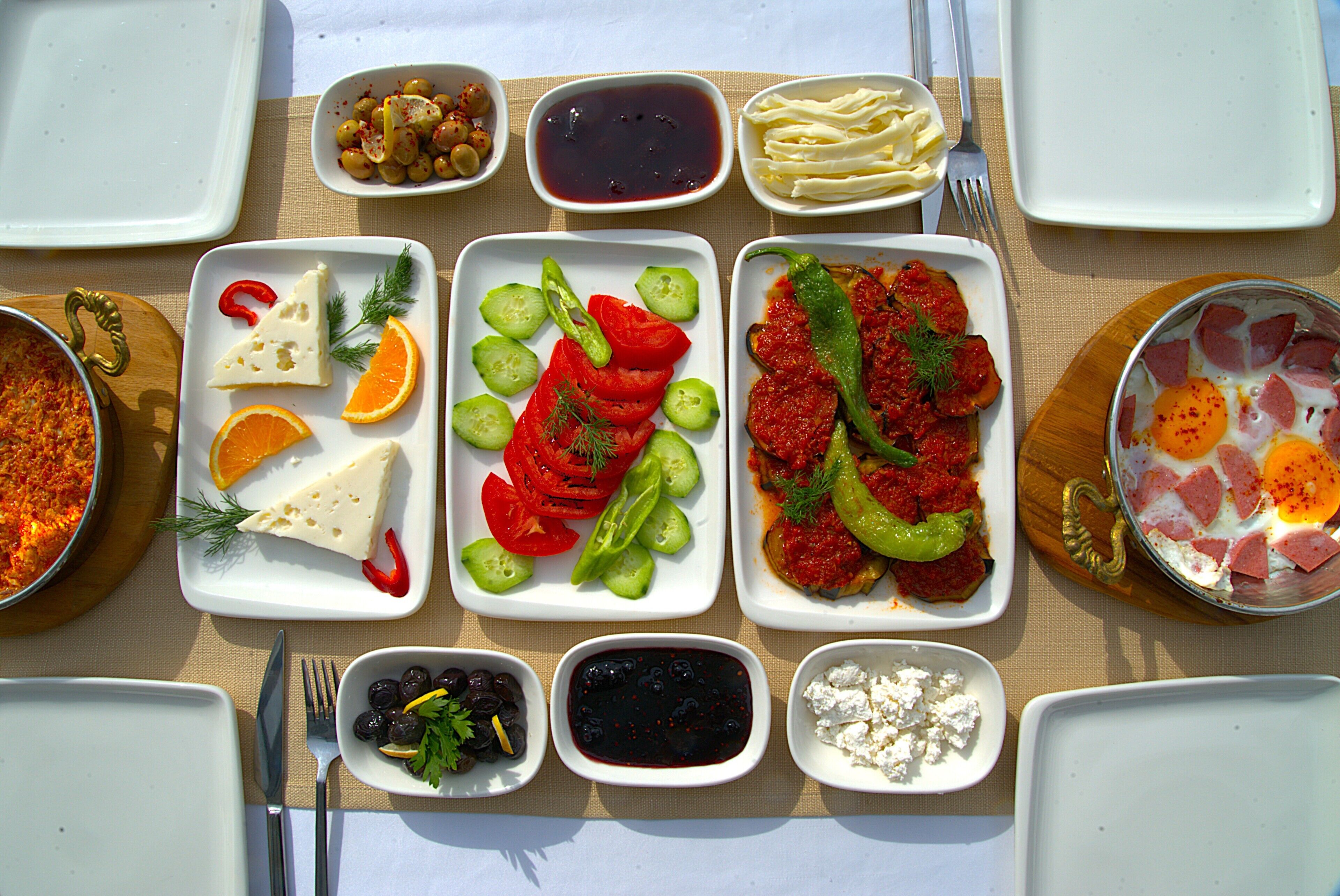 Una mesa puesta con diversos platos que incluyen queso, tomates, pepinos y aceitunas.
