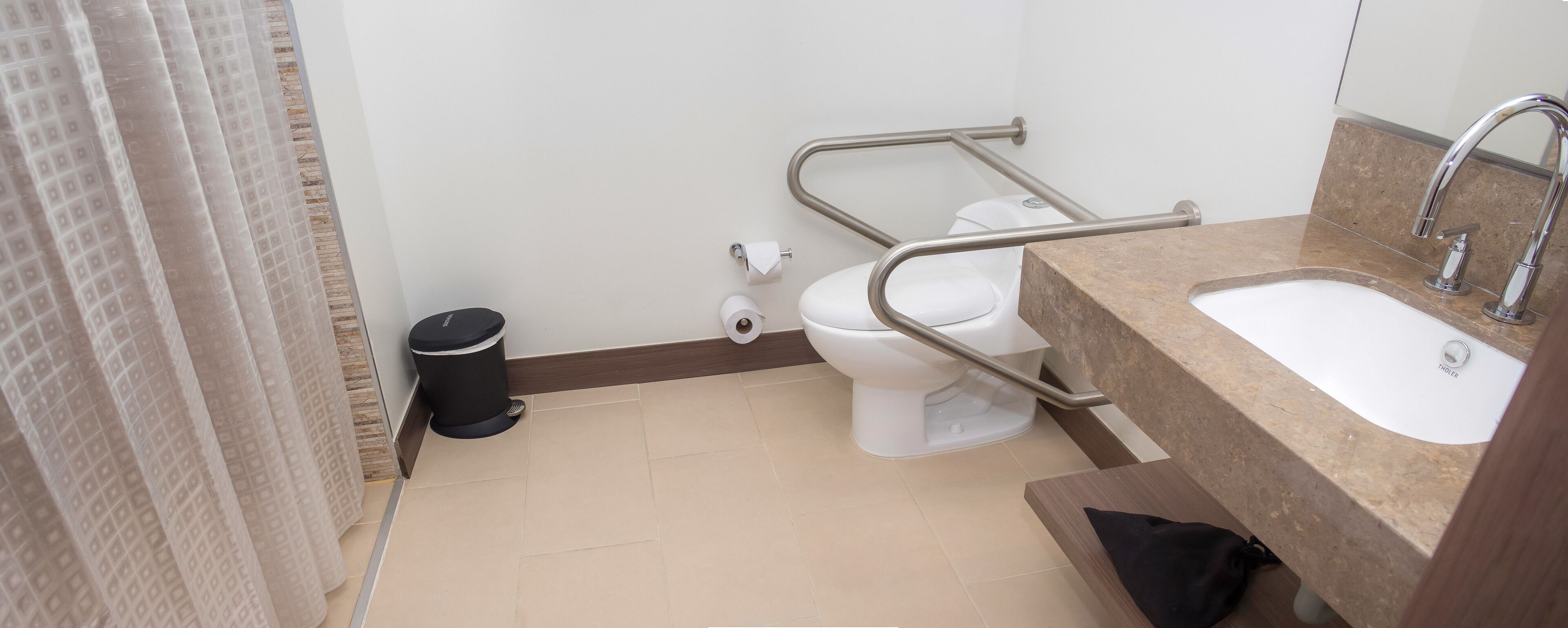 Un baño con inodoro, bidé, lavamanos y cubo de basura.