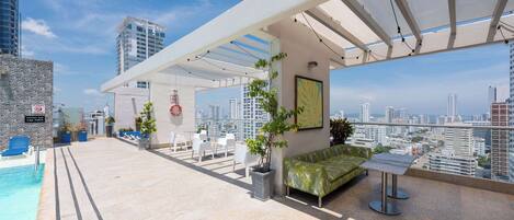 Une terrasse sur le toit avec une piscine, un espace salon et une vue sur la ville.
