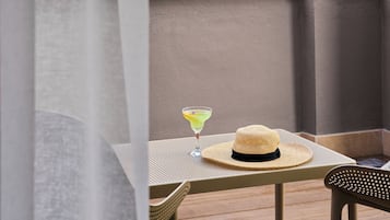 A balcony with a table, a hat, and a drink.