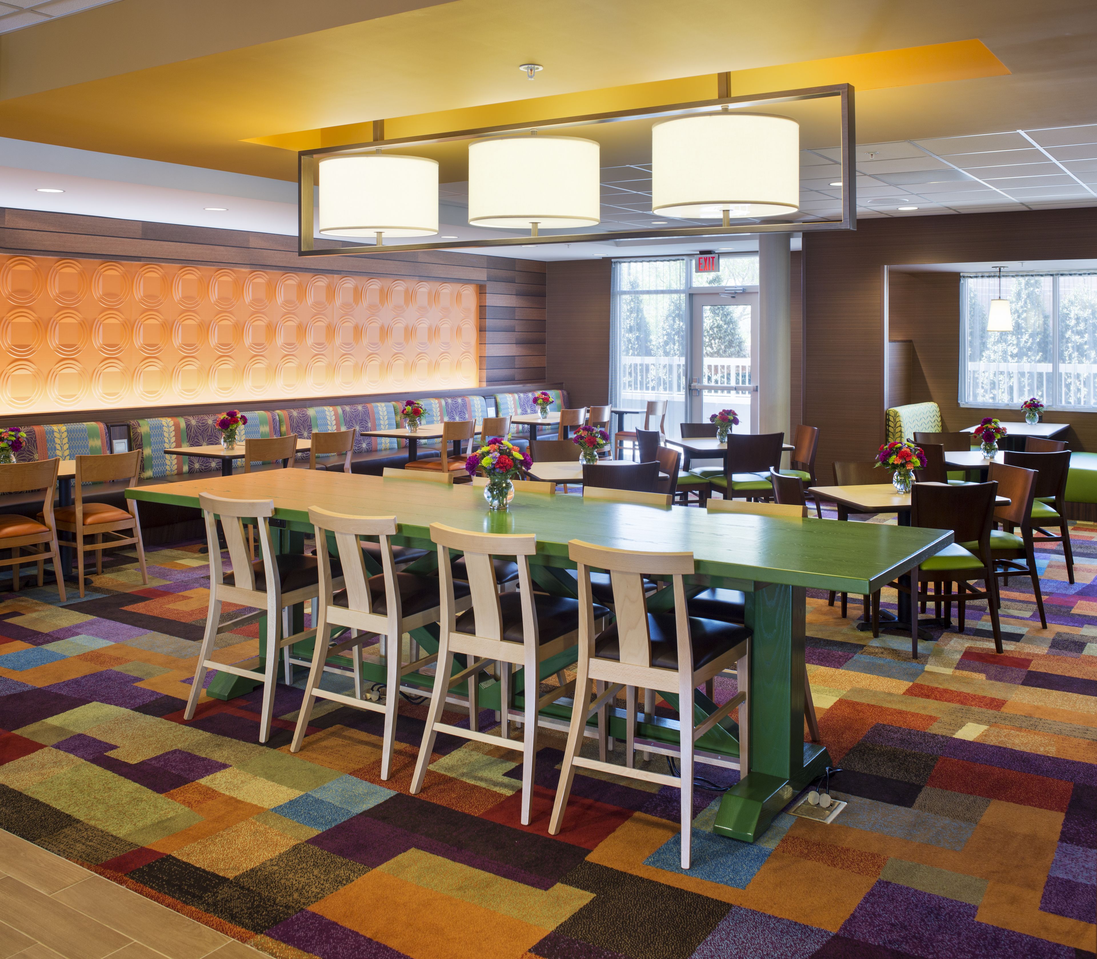 Una hall d'albergo con un'area bar centrale, diverse opzioni di seduta tra cui divanetti e tavoli, e una moquette decorata.