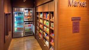 Ein Flur mit einem Corner Market, ausgestattet mit gekühlten Getränkevitrinen und Regalen voller Snacks und Lebensmittel.