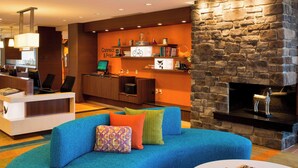 Eine moderne Hotelhalle mit einem blauen Sofa, einem Kamin und einer Rezeption.