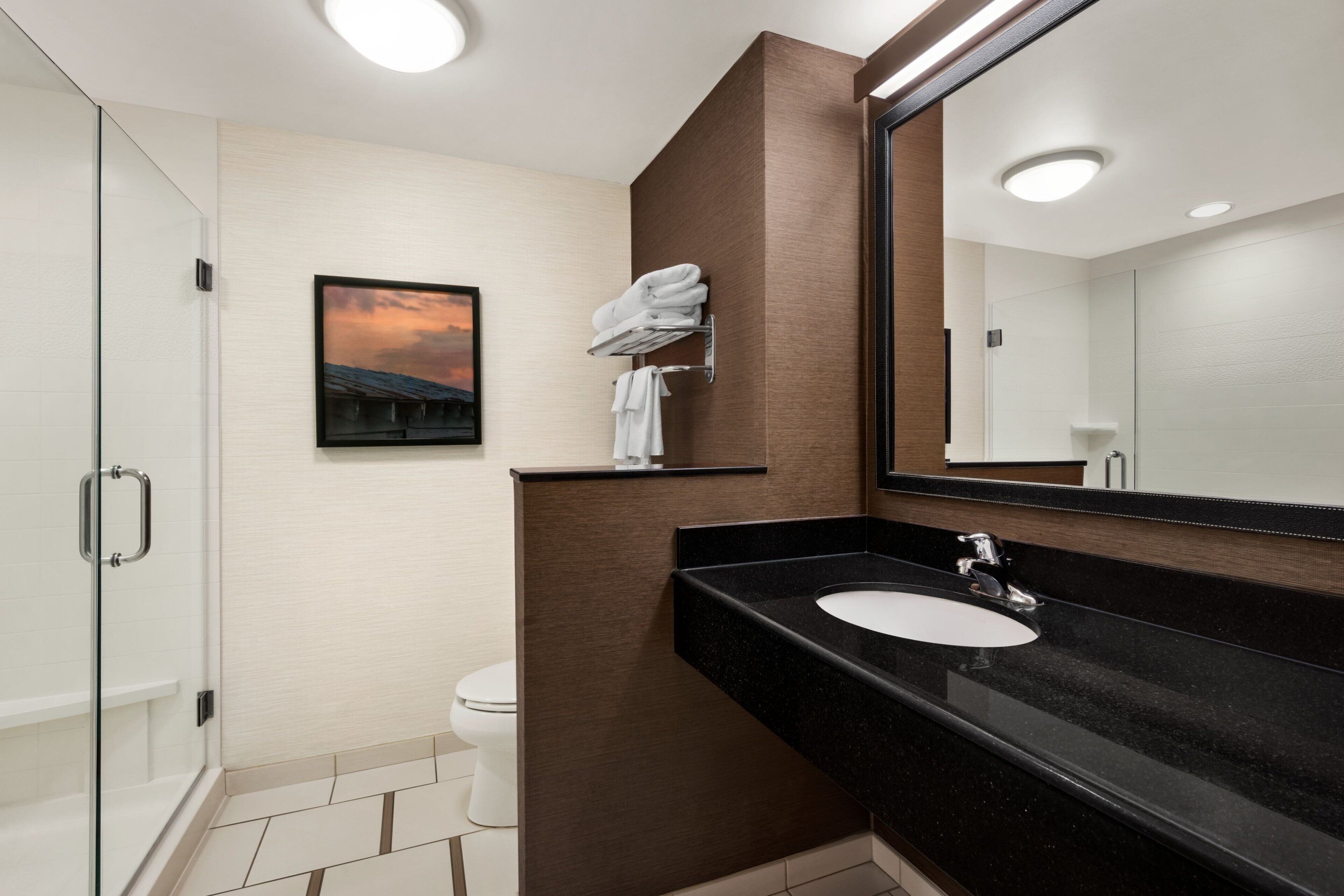 Un bagno moderno con cabina doccia in vetro, lavandino bianco e uno specchio grande.