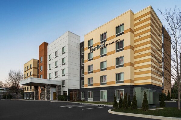 Um hotel Fairfield by Marriott com vários andares e design moderno, apresentando uma combinação de cores bege e marrom, e um estacionamento à frente.