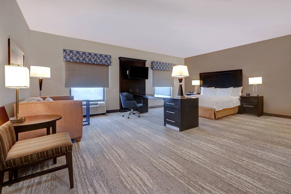 A hotel room with a bed, desk, chair, and a television.