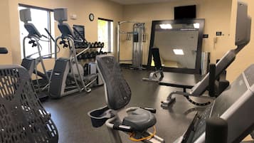 Un gimnasio con cintas de correr, bicicletas estáticas y máquinas de pesas.