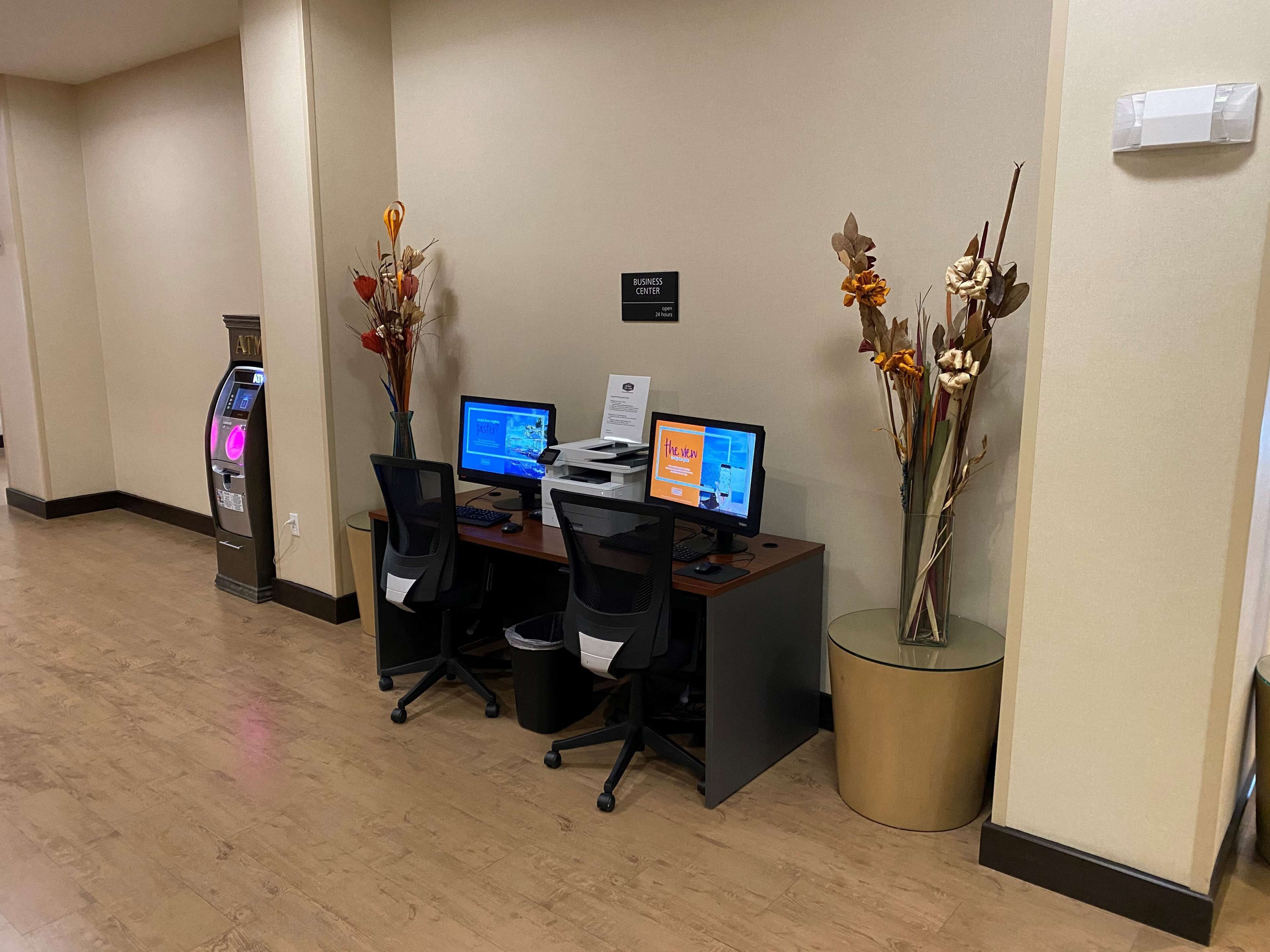 Un centro de negocios con dos estaciones de trabajo por computadora, un mostrador de recepción y un quiosco de auto servicio.