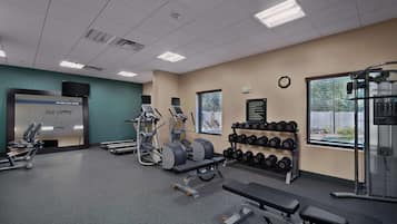 A gym with treadmills, weight machines, and dumbbells.