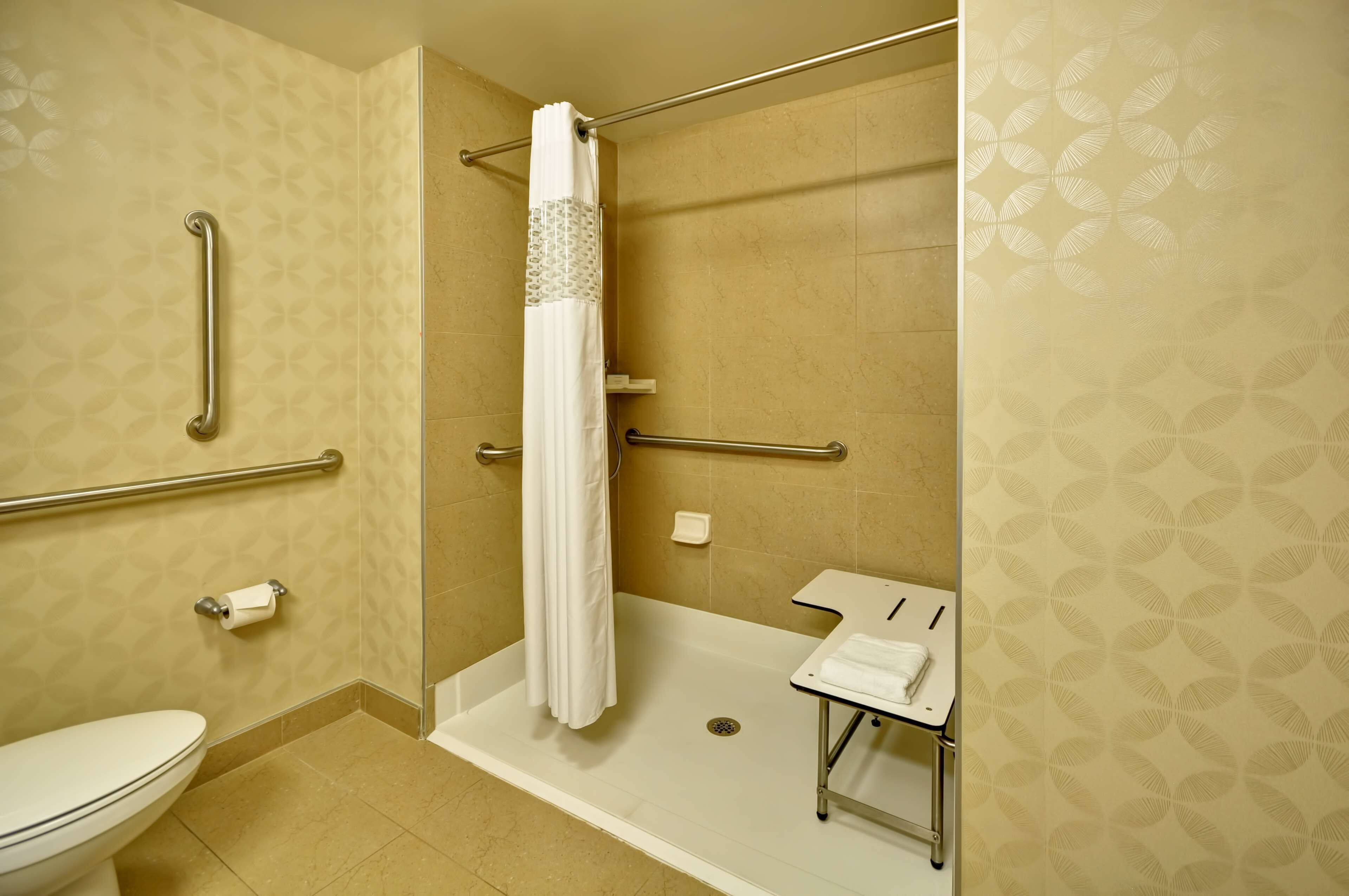Un baño con ducha, inodoro y perchero para toallas.