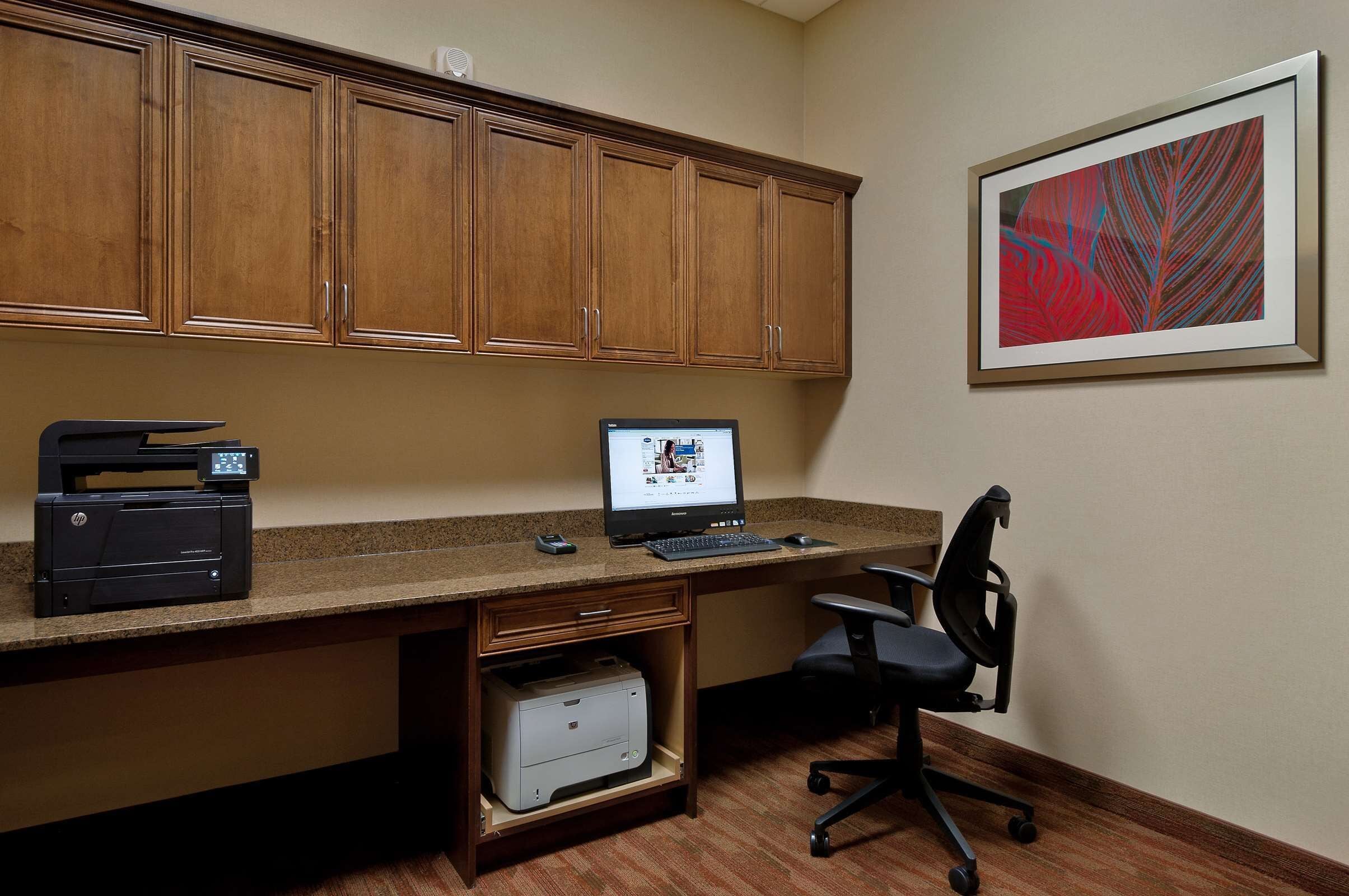 A home office with a desktop computer, printer, and office chair.