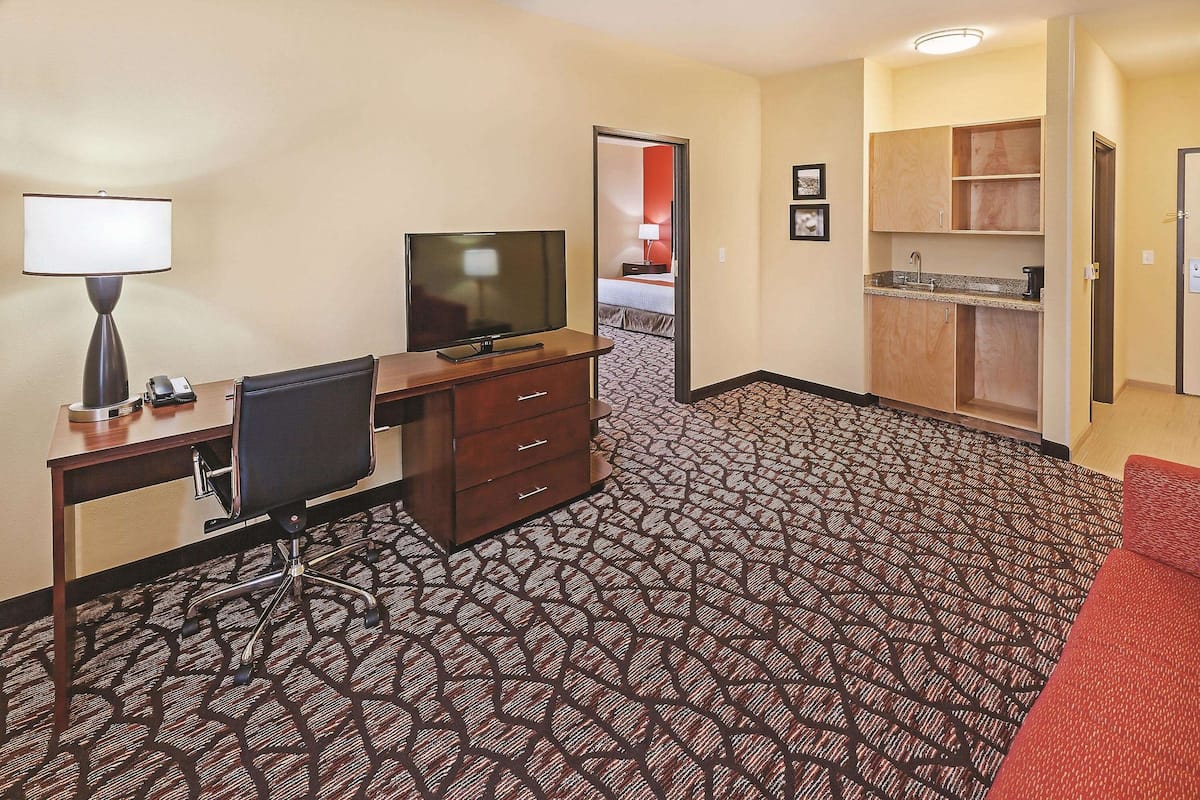 Une chambre d’hôtel équipée d’un bureau, d’une chaise, d’une télévision et d’une kitchenette.