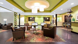 A lobby with a reception desk, seating area, and a decorative wall. - La Quinta Inn & Suites by Wyndham Pecos (Pecos)