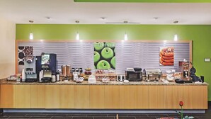 A breakfast bar with coffee machines, a pastry display, and a sign for 'La Quinta'. - La Quinta Inn & Suites by Wyndham Pecos (Pecos)