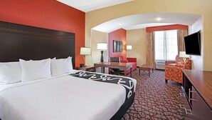 A hotel room with a large bed, a desk, a chair, a TV, and a window with curtains. - La Quinta Inn & Suites by Wyndham Pecos (Pecos)