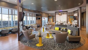 A spacious lobby with a curved ceiling, seating areas, a reception desk, and large windows offering views. - SpringHill Suites by Marriott Midland Odessa (Midland)