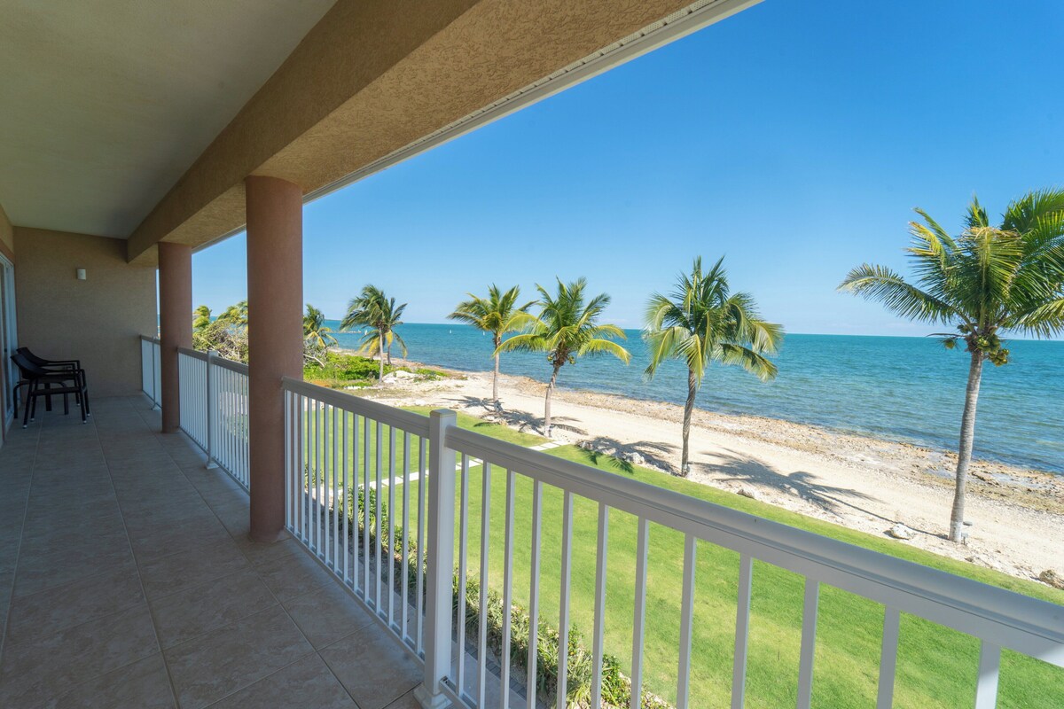 A balcony with a view of the beach and ocean.