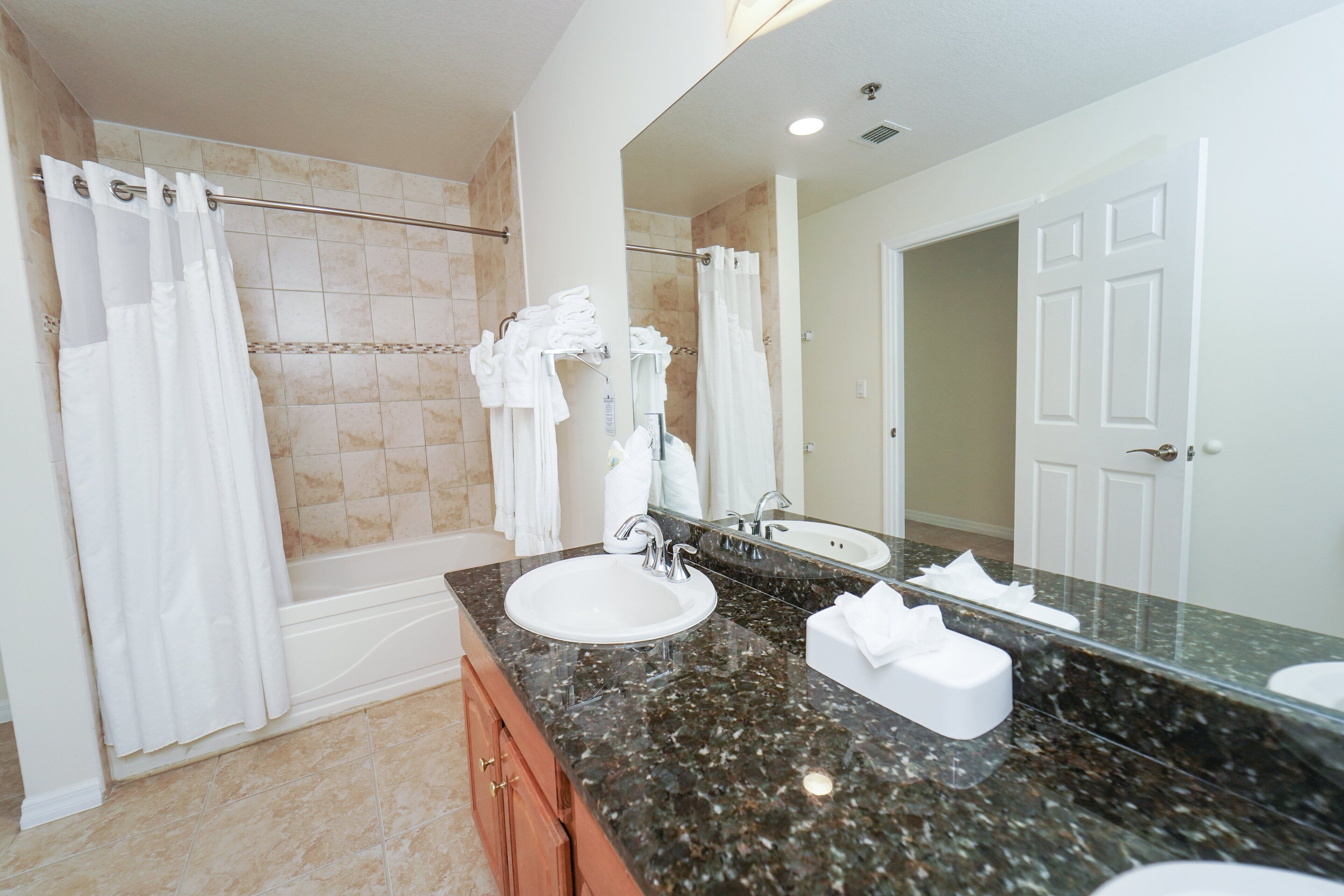 A bathroom with a double sink, a large mirror, a shower with a glass door, and a towel rack.