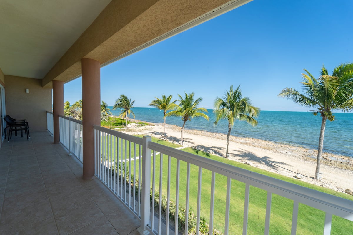 A balcony with a view of the beach and ocean.