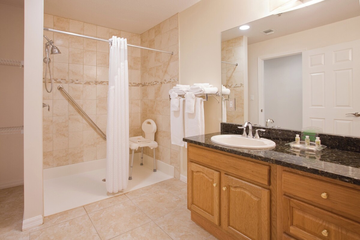 A bathroom with a shower, toilet, sink, and wooden cabinets.