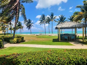 A beachside resort with a thatched gazebo, palm trees, and a clear view of the ocean. - Holiday Inn Resort Grand Cayman by IHG (West Bay)