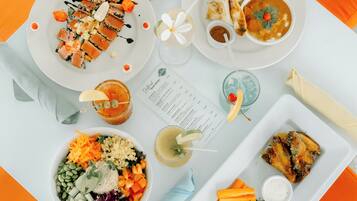 A table with various dishes including sushi, soup, and a salad, along with a menu and drinks.