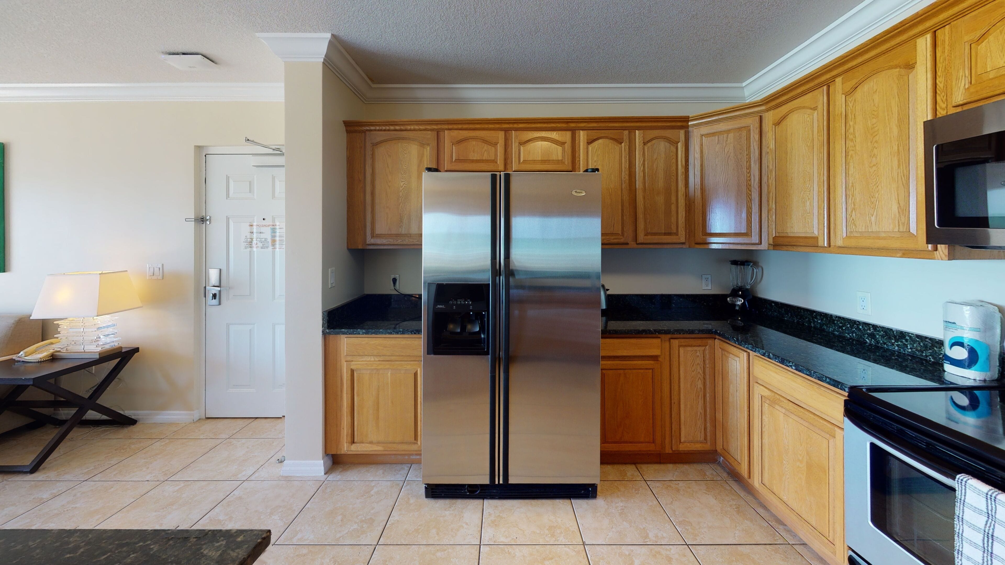A kitchen with wooden cabinets, a stainless steel refrigerator, a microwave, and an oven.