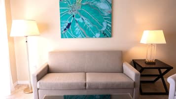 A living room with a beige sofa, two side tables with lamps, and a wall-mounted abstract painting.