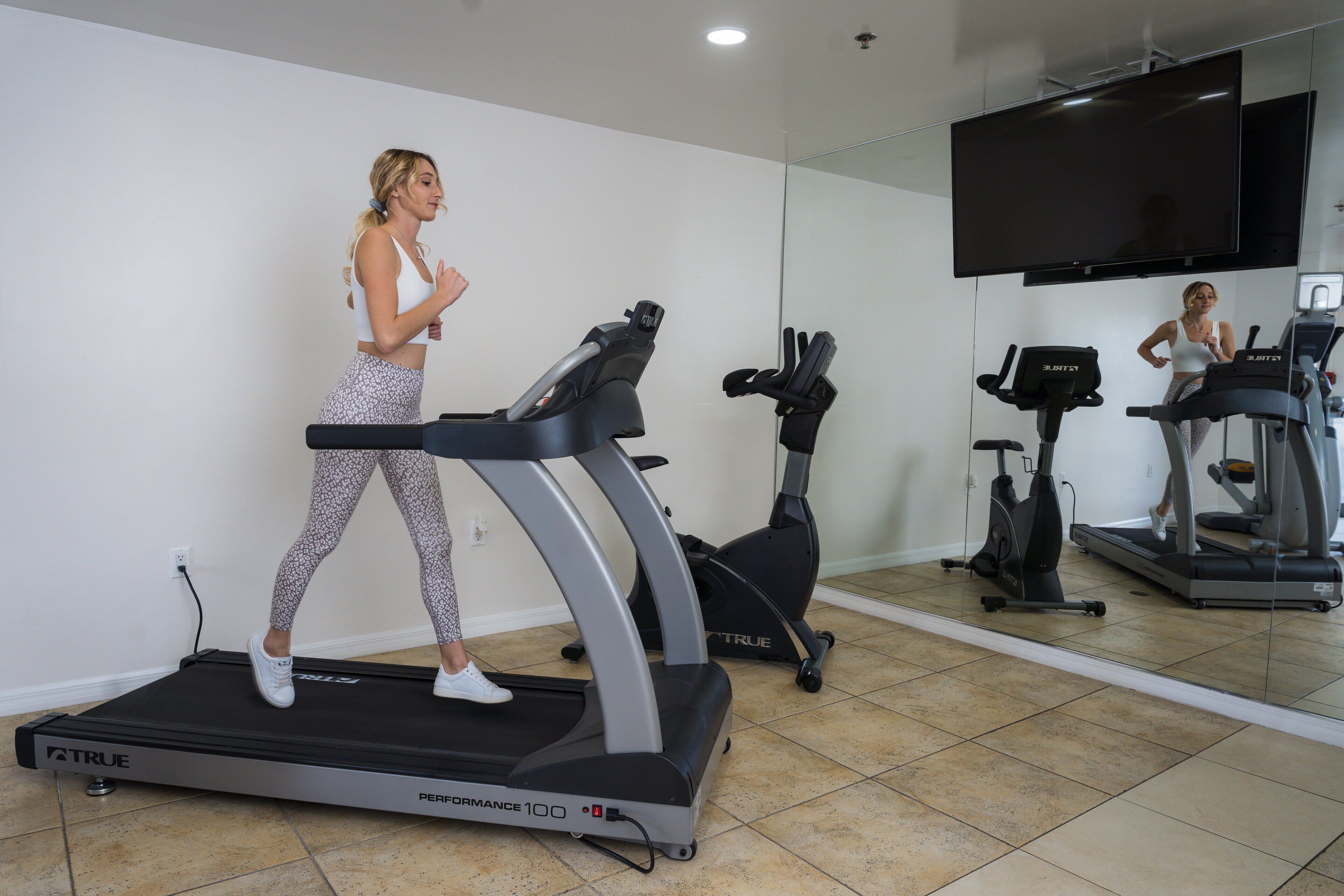 Une salle de sport équipée d’un tapis de course, d’un vélo elliptique et d’un vélo d’appartement.