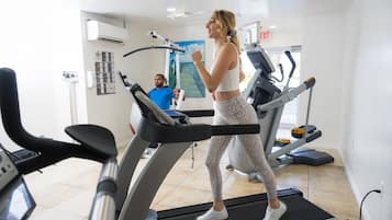 Une salle de sport avec des tapis de course, un homme qui s'entraîne et une femme qui marche sur un tapis de course.