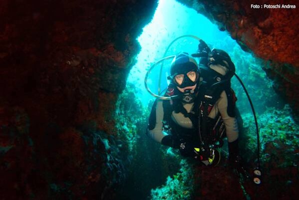 Un buceador en una cueva con casco y equipo de buceo.