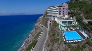 Ein Hotel an der Küste mit Pool, einer kurvenreichen Straße und Meerblick.