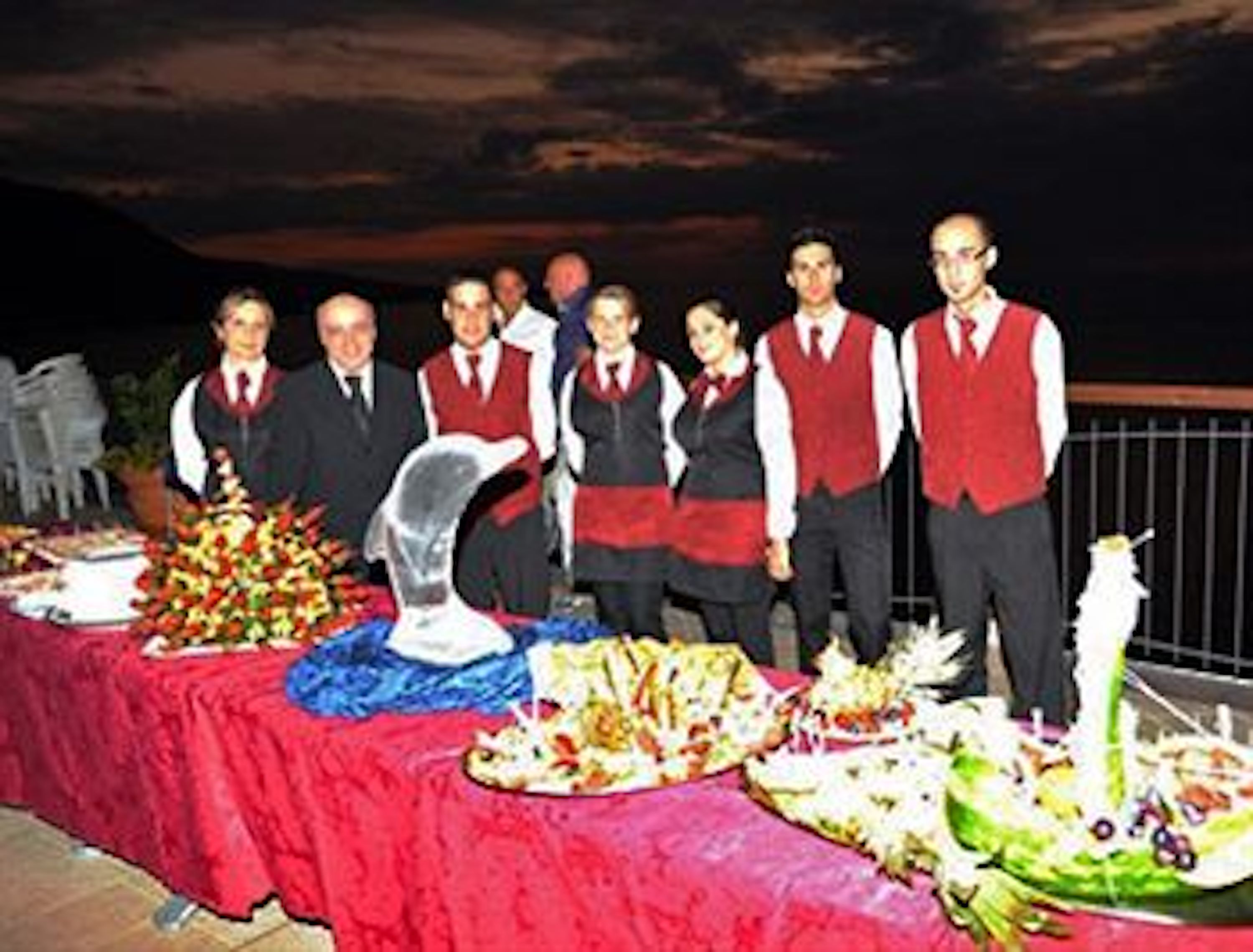 A group of people in formal attire standing at a buffet table with various dishes.