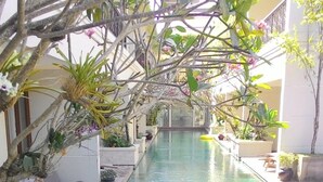 A pool area with lounge chairs and potted plants. - Seminyak Lagoon All Suites Hotel (Keroboken Kelod)