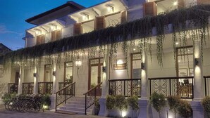 A hotel with a covered outdoor area, a staircase, and potted plants.