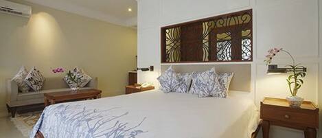 A bedroom with a large bed, a sofa, a nightstand, and a decorative panel on the wall.