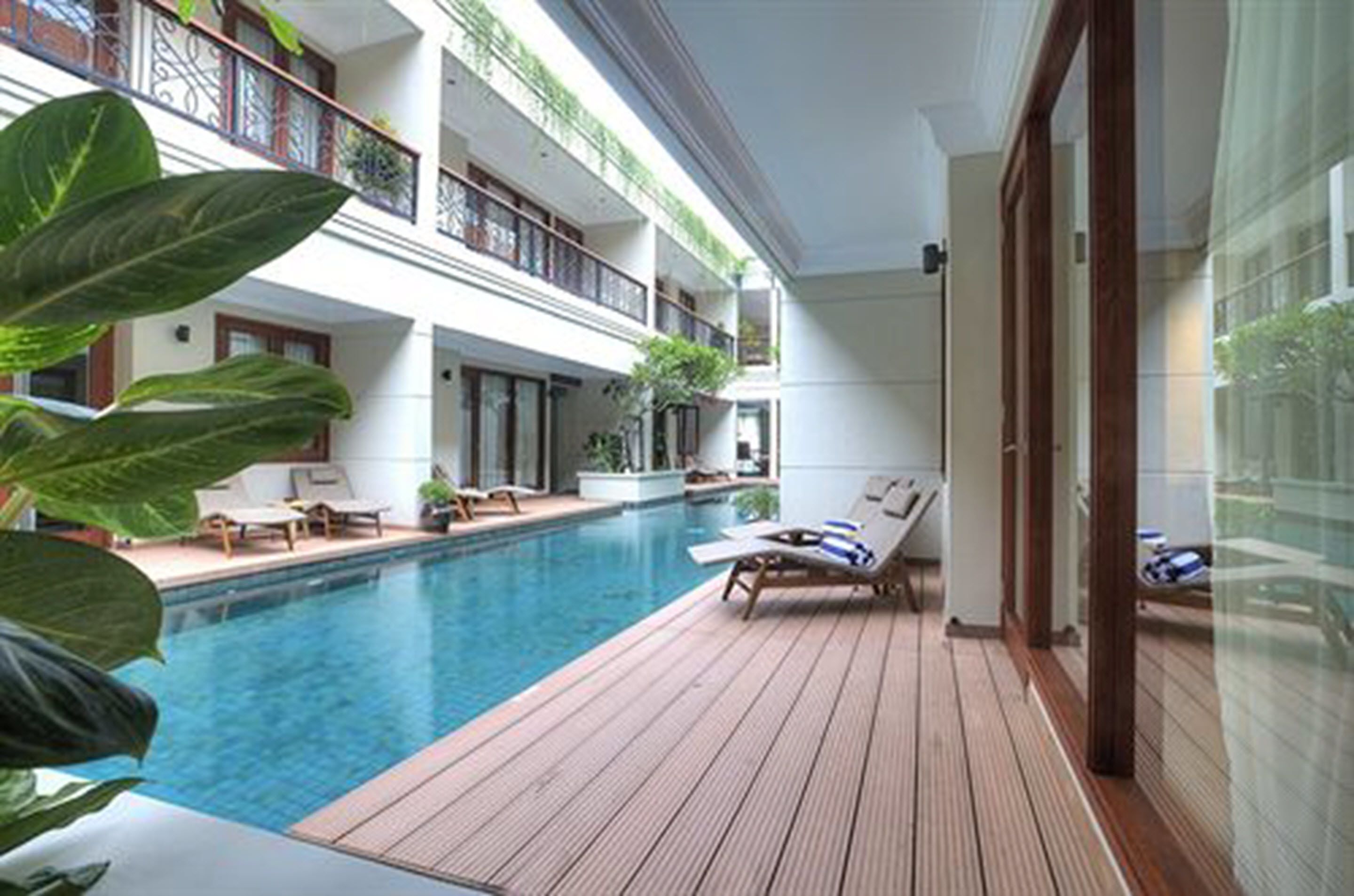 A pool area with lounge chairs and a wooden deck.