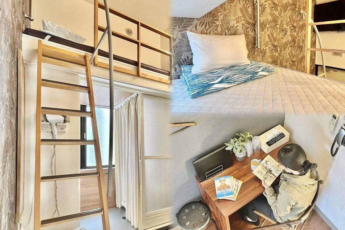 A bunk bed with a ladder, a desk with a laptop, and a small table with a remote control and a book.